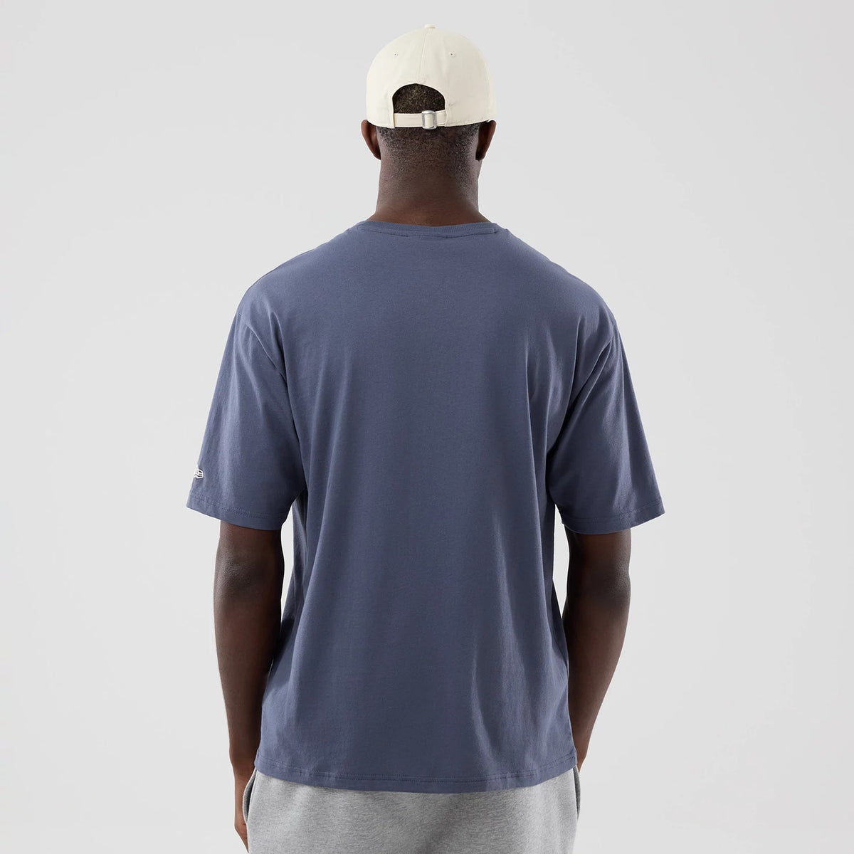New Era LA Dodgers MLB Graphic Grey Oversized T-Shirt, back view on a model with a neutral cap, showing the plain grey back of the oversized t-shirt and a short sleeve with an embroidered logo near the hem.