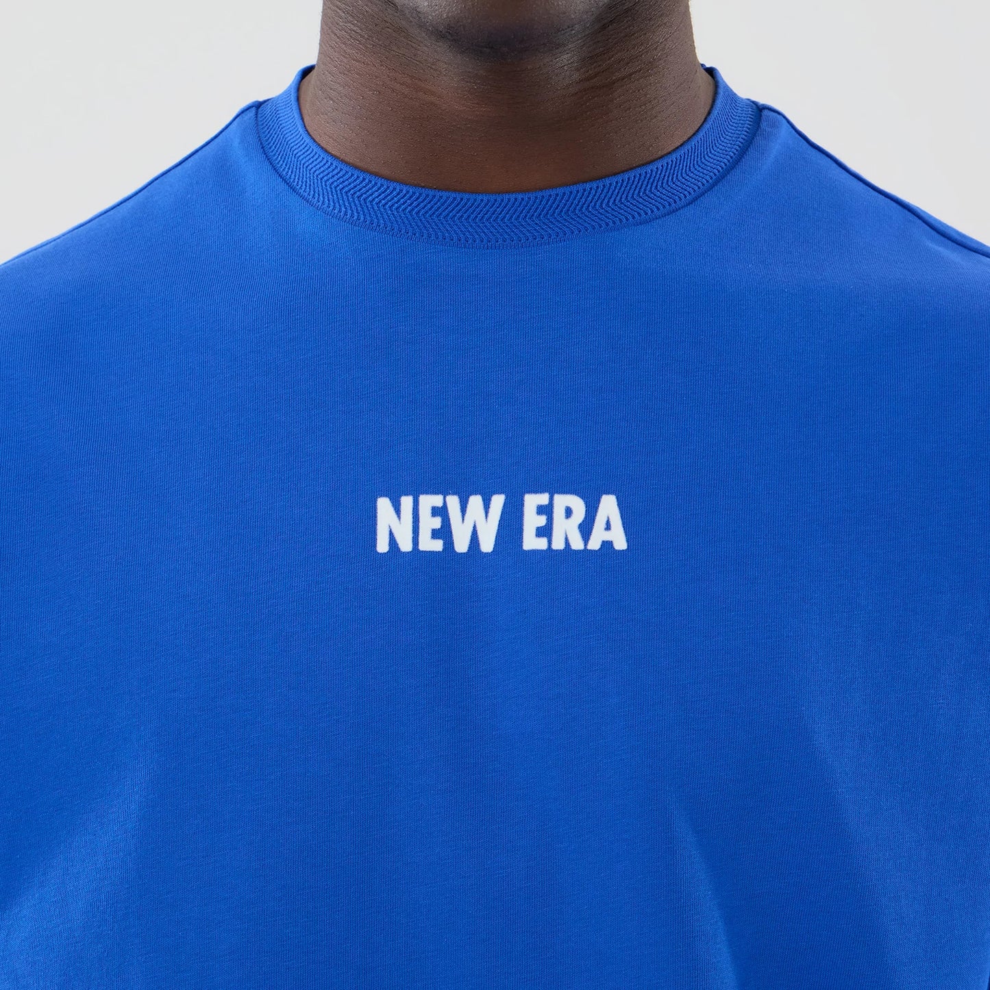The model is wearing this New Era Cap Graphic Oversized T-Shirt in bright blue. 5