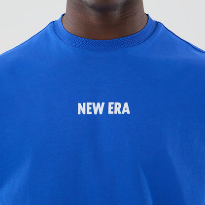 The model is wearing this New Era Cap Graphic Oversized T-Shirt in bright blue. 5