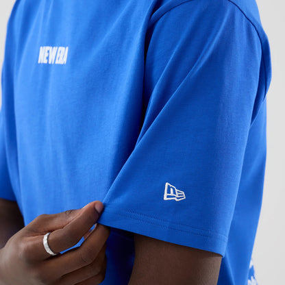 The model is wearing this New Era Cap Graphic Oversized T-Shirt in bright blue. 7