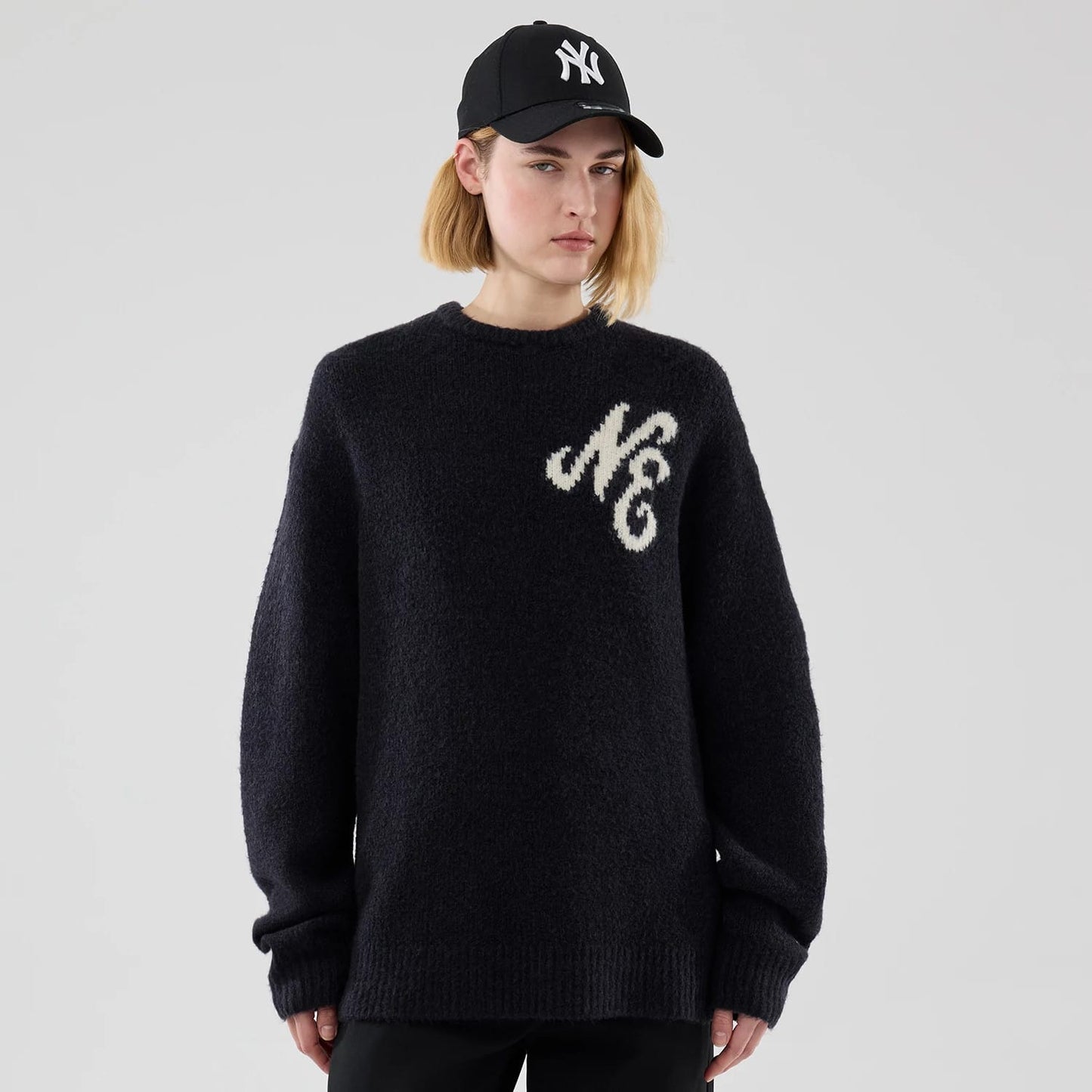 The model is wearing this New Era Knit Heritage Knitted Sweater in navy. 4