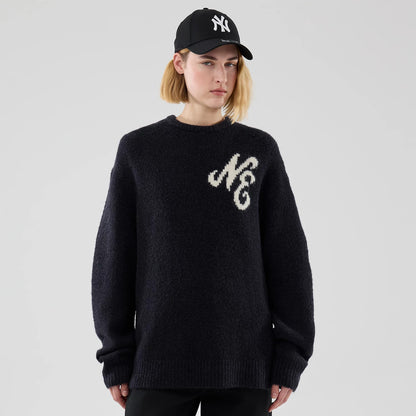 New Era Knit Heritage Navy Knitted Sweater, front view on a model wearing a black New Era cap, featuring a large white NE design embroidered on the left chest and a ribbed hem and cuffs.