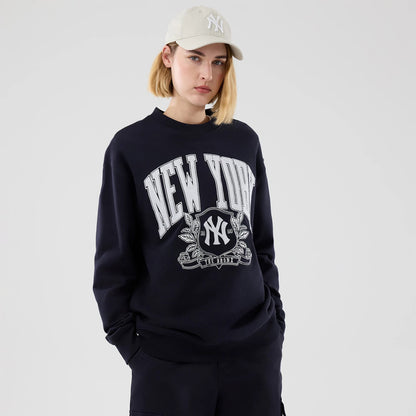 New Era New York Yankees MLB Arch Graphic Navy Oversized Crew Neck Sweater, front view on a model wearing a beige cap, featuring white New York lettering across the chest, the Yankees logo encircled by a decorative graphic, and long sleeves.