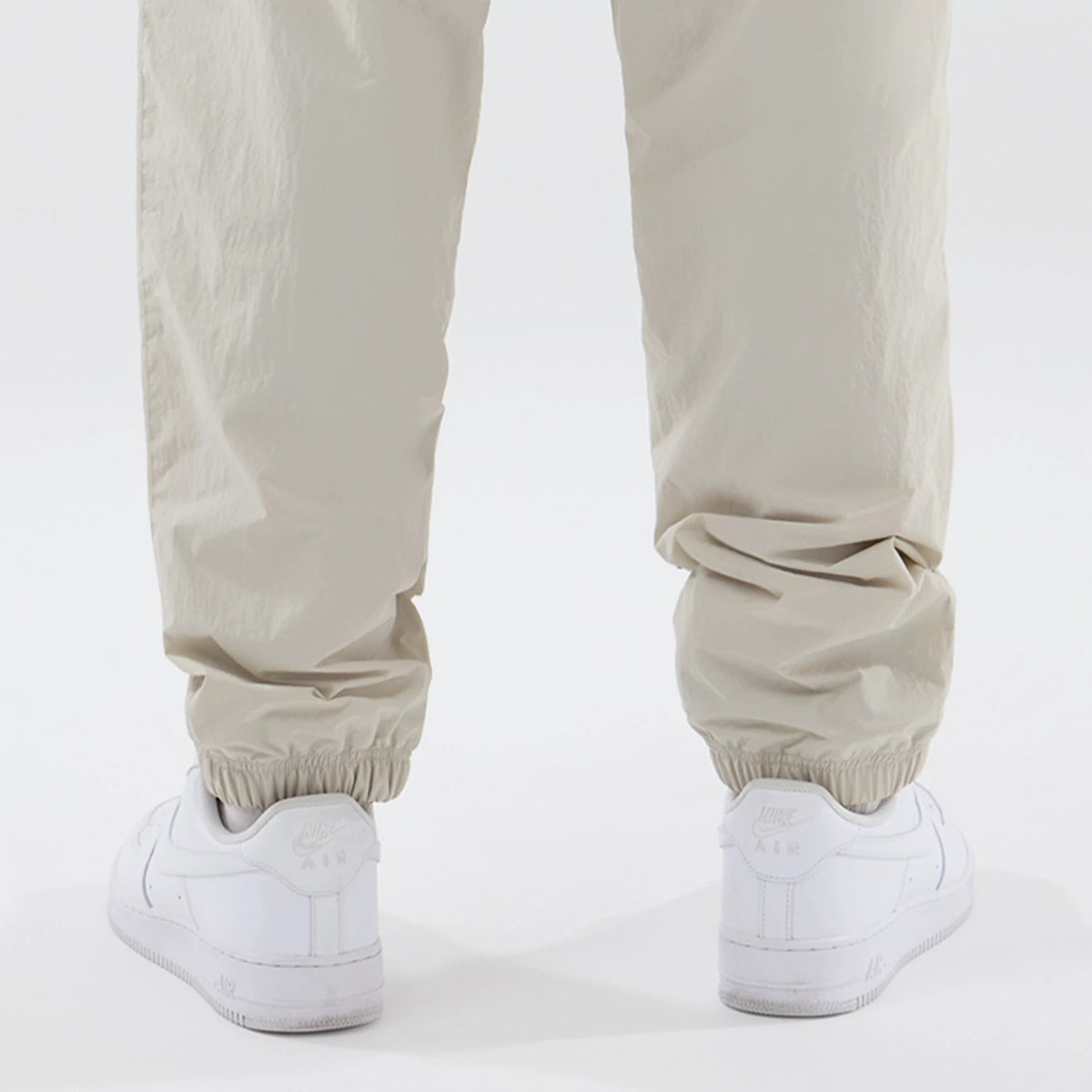 New Era New York Yankees MLB Piping Track Cream Track Pants, back view showing the elasticated cuffs resting above white sneakers, with a loose fit and fabric texture, emphasising a casual and sporty look.