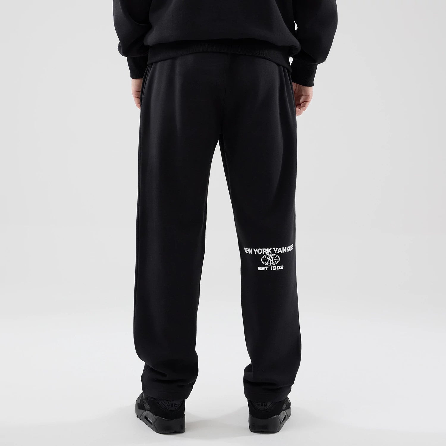 The model is wearing these MLB Logo Graphic New York Yankees Straight Leg Joggers in black. 2