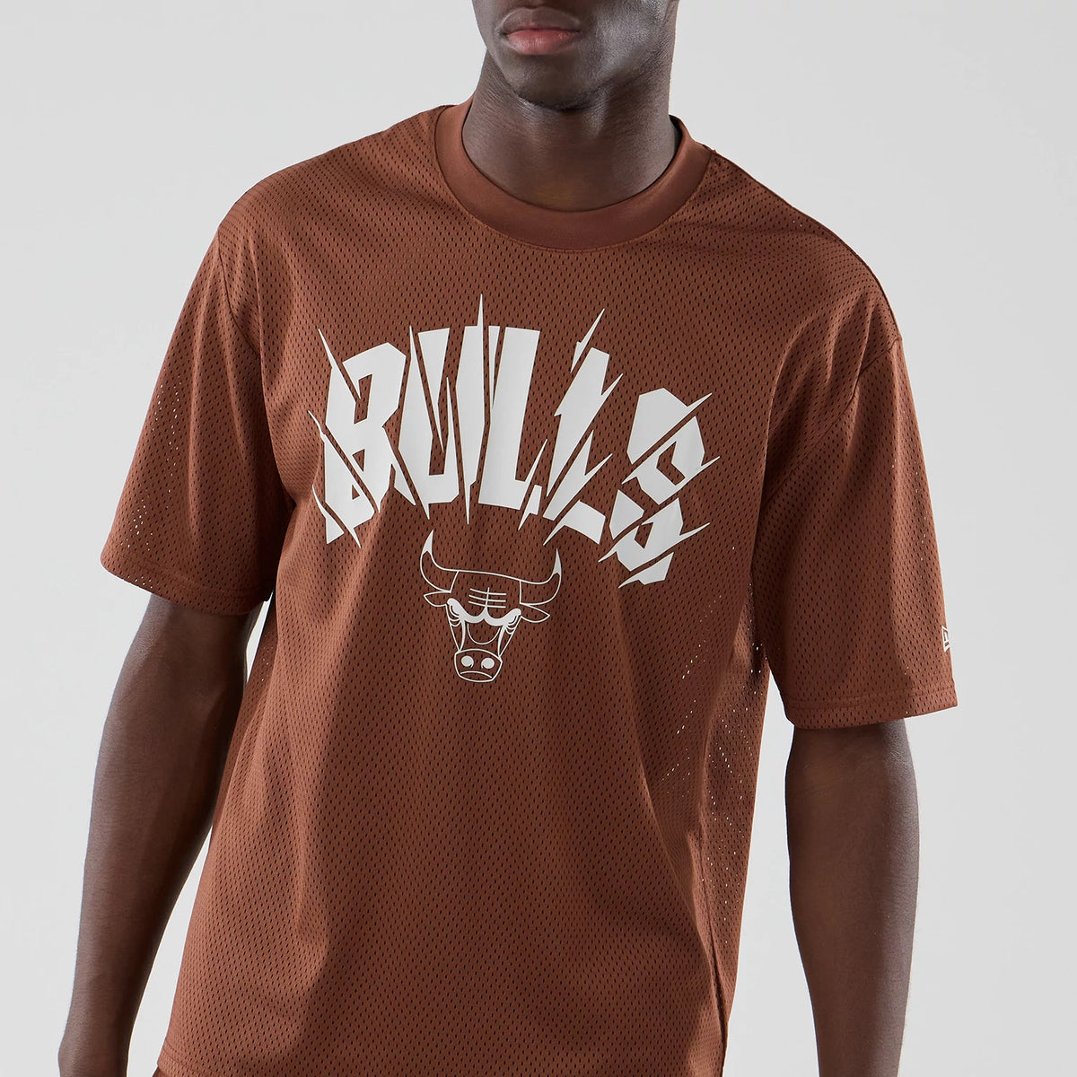 New Era Chicago Bulls NBA Core Plus Mesh Brown Oversized T-Shirt, front view showing the large white Bulls graphic with a basketball-inspired font, the bull head logo beneath, and the New Era logo embroidered on the left sleeve.