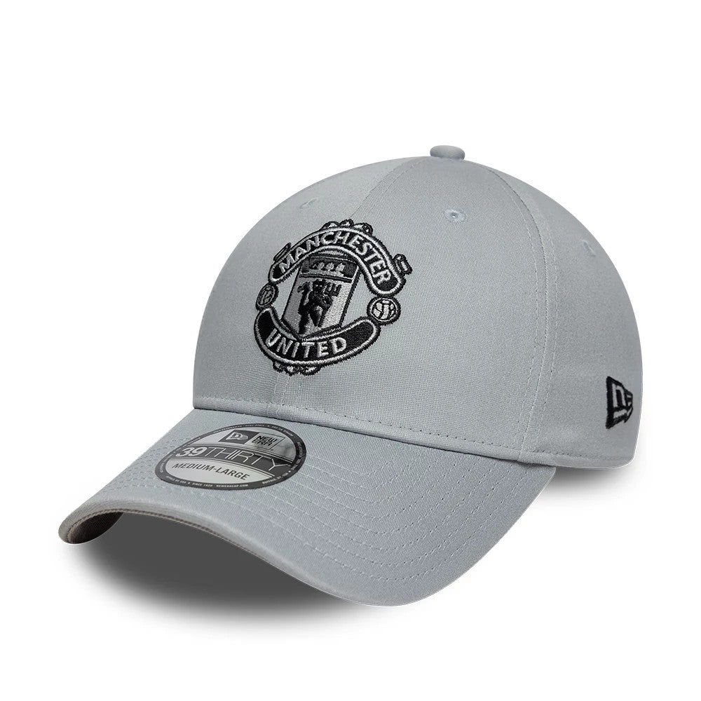Manchester United FC Grey New Era 39THIRTY Stretch Fit Cap, three-quarter view showing the black embroidered Manchester United crest on the front panel, grey curved visor with a 39THIRTY size sticker, and black New Era flag logo on the left side.