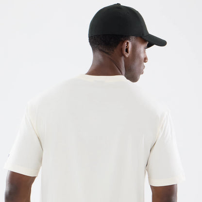 New Era Denver Broncos NFL Sport Classic Cream T-Shirt, back view on-model showing the plain cream back, short sleeves with ribbed cuffs, and a small embroidered New Era logo on the left sleeve, paired with a plain black cap.