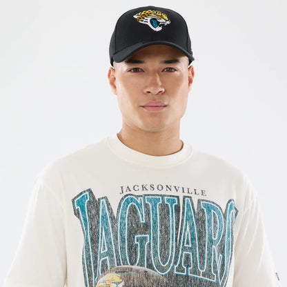 New Era Jacksonville Jaguars NFL Sport Classic Cream T-Shirt, front view on a model styled with a black cap, featuring teal and black Jaguars lettering across the chest with a jaguar graphic below, on an oversized cream shirt.