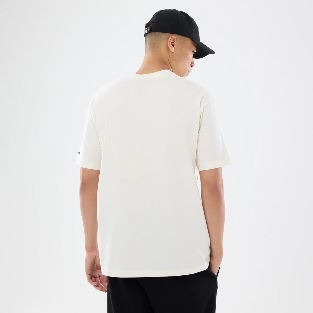 New Era Jacksonville Jaguars NFL Sport Classic Cream T-Shirt, back view on a model with a black cap, showcasing the plain cream back of the t-shirt, short sleeves, and a small embroidered New Era logo on the left sleeve edge.