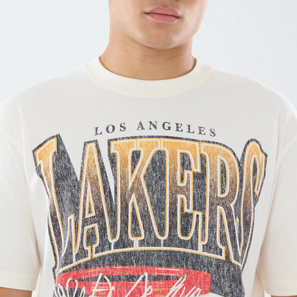 New Era LA Lakers NBA Sport Classic Cream T-Shirt, front view on-model showing a graphic logo with LAKERS in large, distressed lettering across the chest, LOS ANGELES in smaller text above, and additional red and black accents below.
