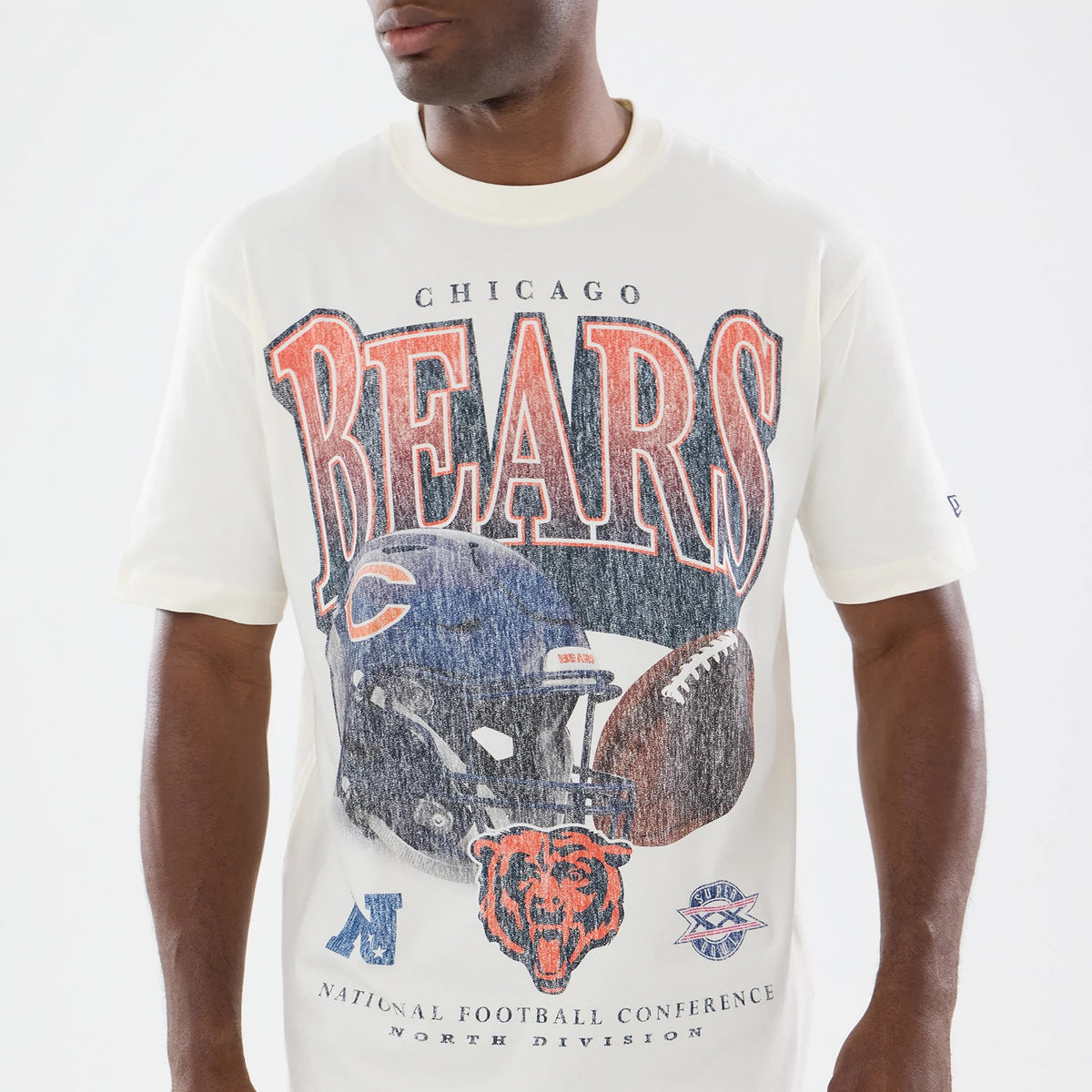 New Era Chicago Bears NFL Sport Classic Cream T-Shirt, front view on a model showing distressed Bears lettering in orange and navy, an illustrated helmet with a football graphic, and a small embroidered New Era logo on the left sleeve.