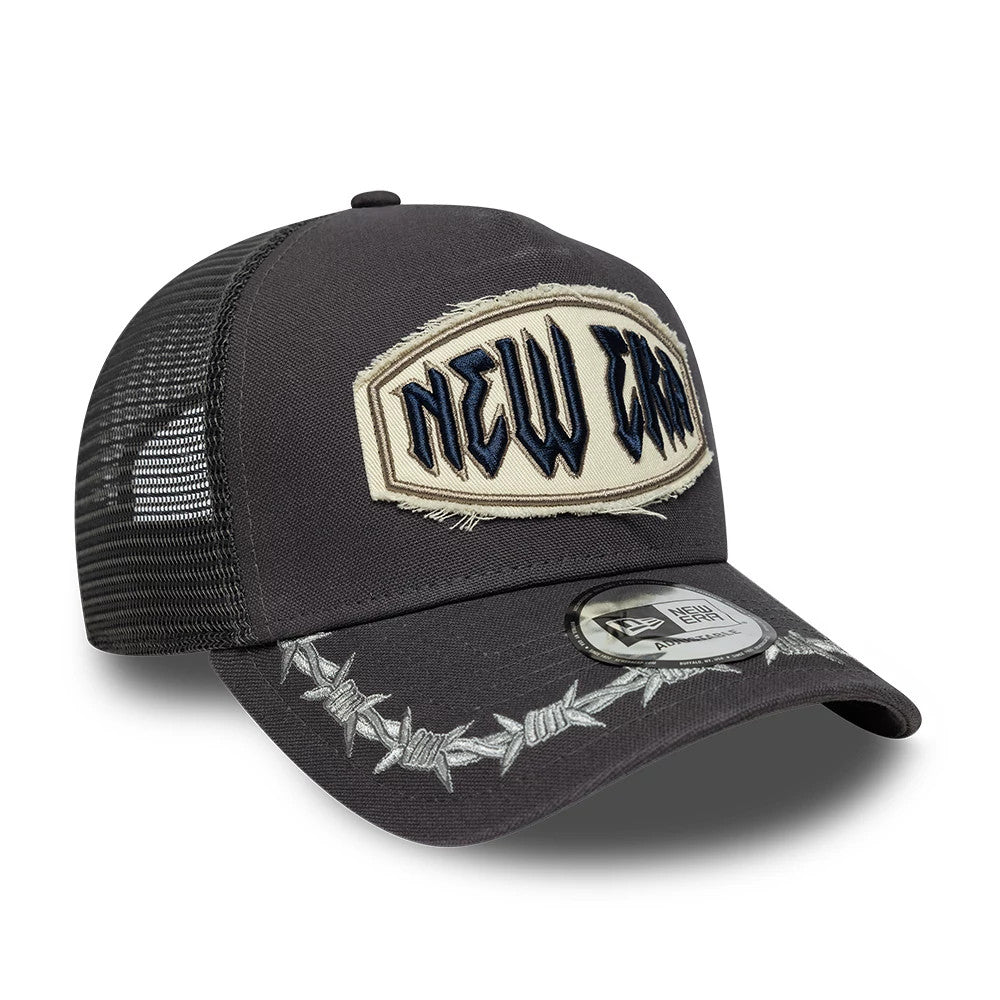 New Era Distressed Patch Charcoal 9FORTY E-Frame Trucker Adjustable Cap, front view showing a large embroidered patch with frayed edges on the front panel, silver barbed wire design on the curved visor and a 9FORTY size sticker.