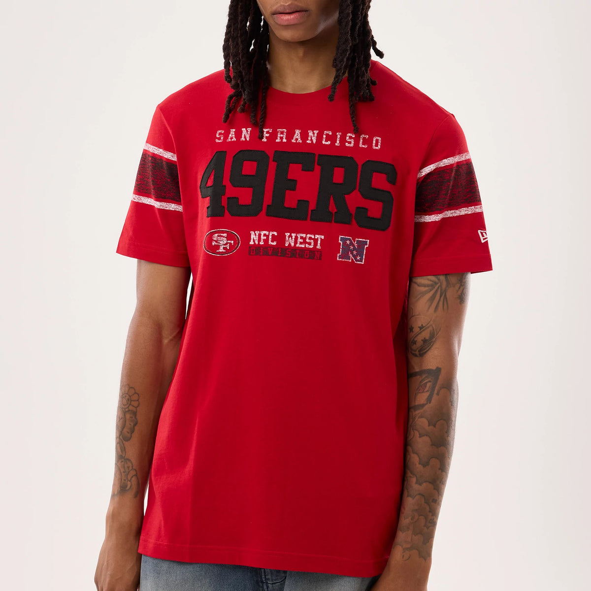 New Era San Francisco 49ers NFL Sideline 2026 Red T-Shirt, front view on a model showcasing large black 49ERS lettering across the chest, SAN FRANCISCO above, with additional printed logos and striped on the sleeves.