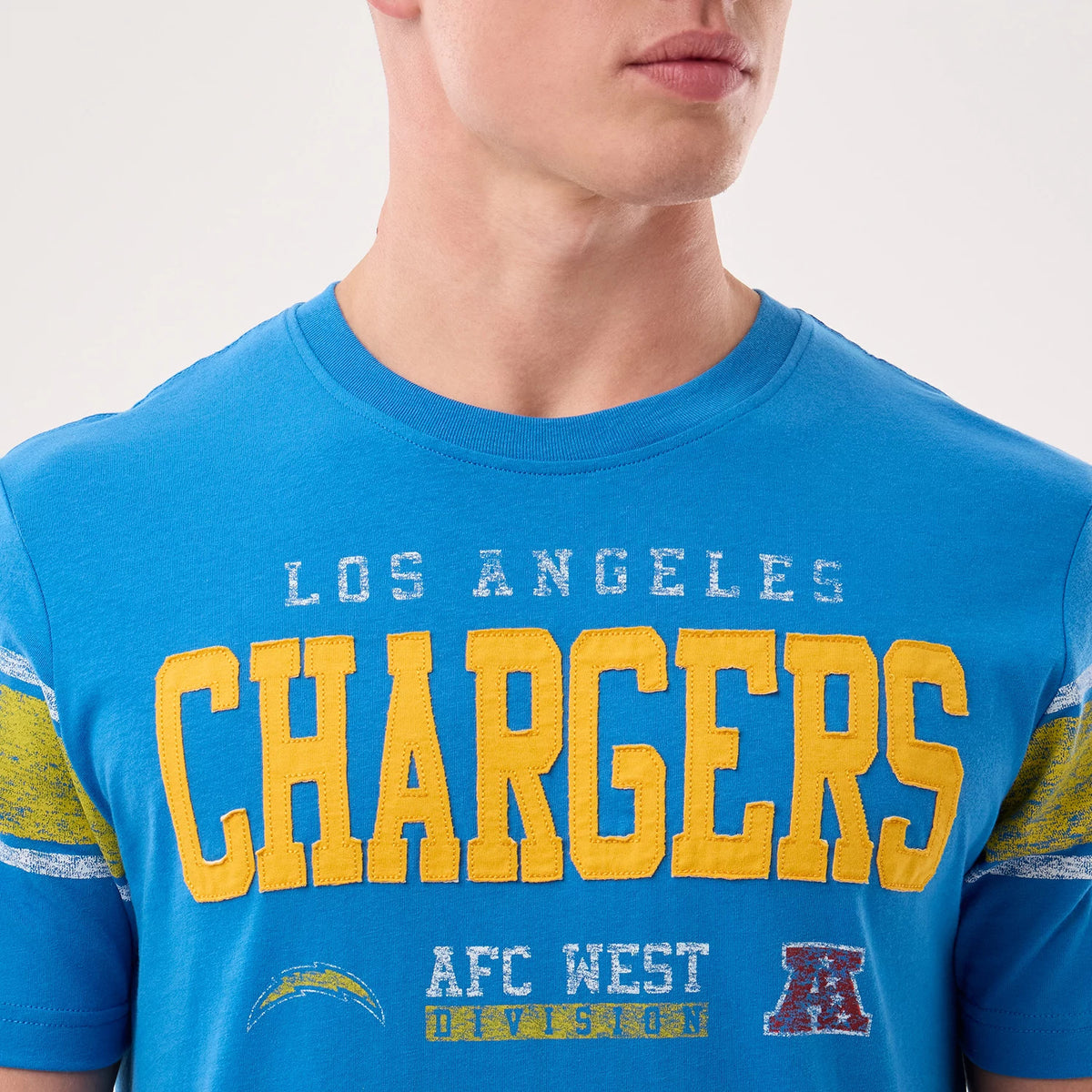 New Era LA Chargers NFL Sideline 2026 Blue T-Shirt, front view on-model showing large yellow Chargers lettering across the chest, white Los Angeles text above, and a small embroidered Chargers logo below with striped on the sleeves.