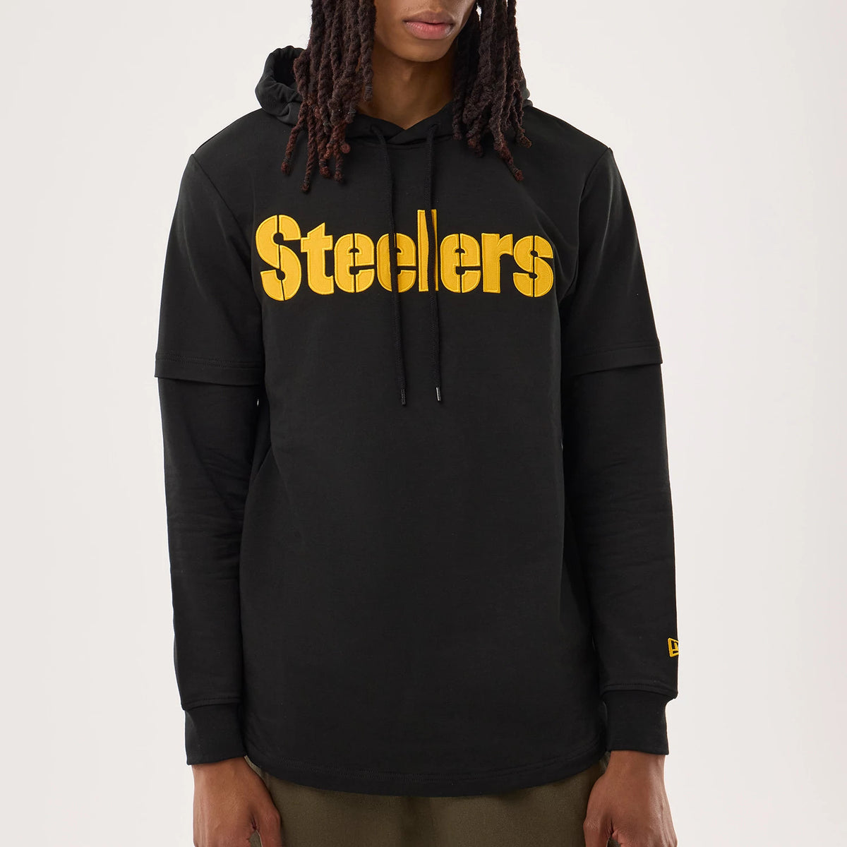 New Era Pittsburgh Steelers NFL Sideline 2026 Black Double Sleeve Hoodie, front view on a model highlighting the yellow Steelers lettering across the chest, double sleeve design with black drawstrings on the hood.