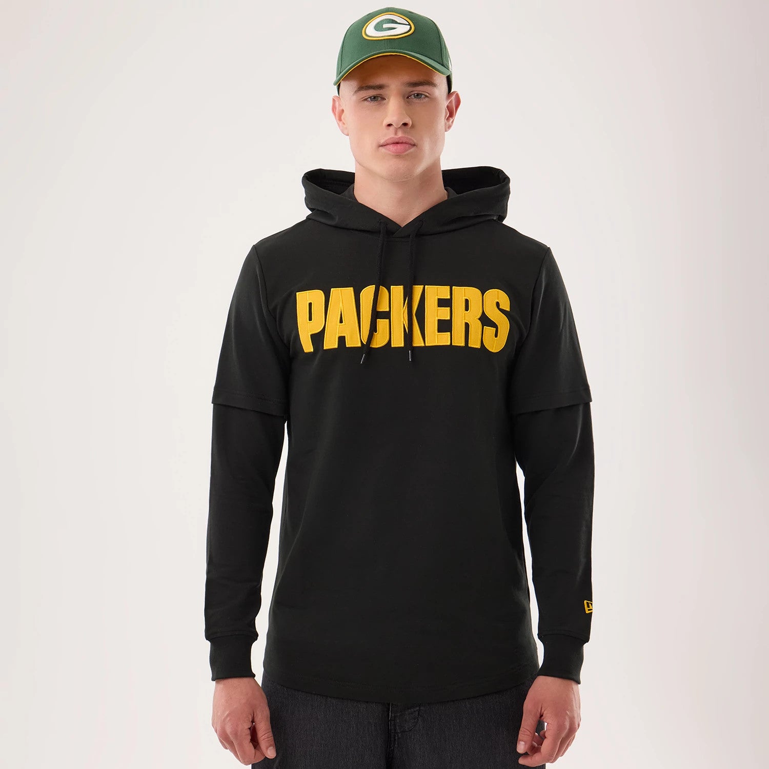 The model is wearing this NFL Sideline 2026 Green Bay Packers Double Sleeve Hoodie in black. 1