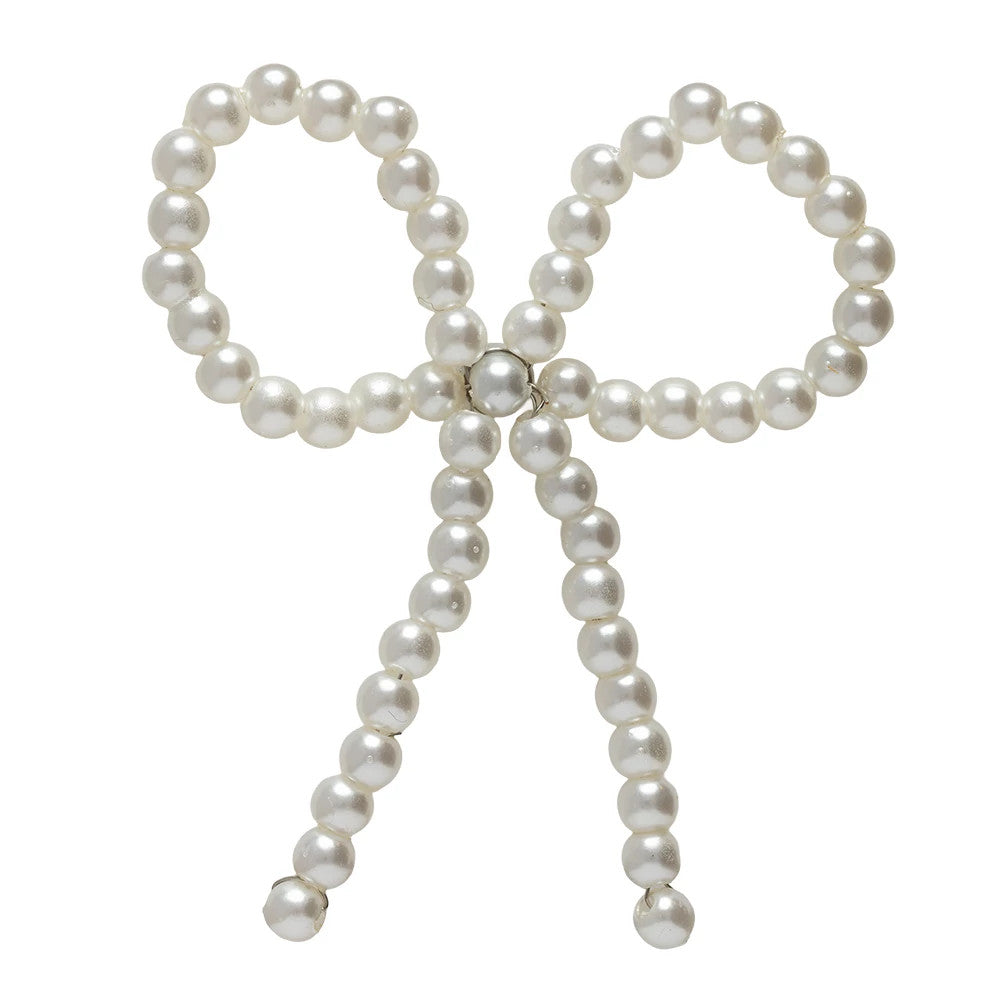 New Era Faux Pearl Bow White Pin Badge, front view showing a delicate bow shape crafted with faux white pearls forming symmetrical loops at the top and cascading strands, with a central cluster securing the structure elegantly.