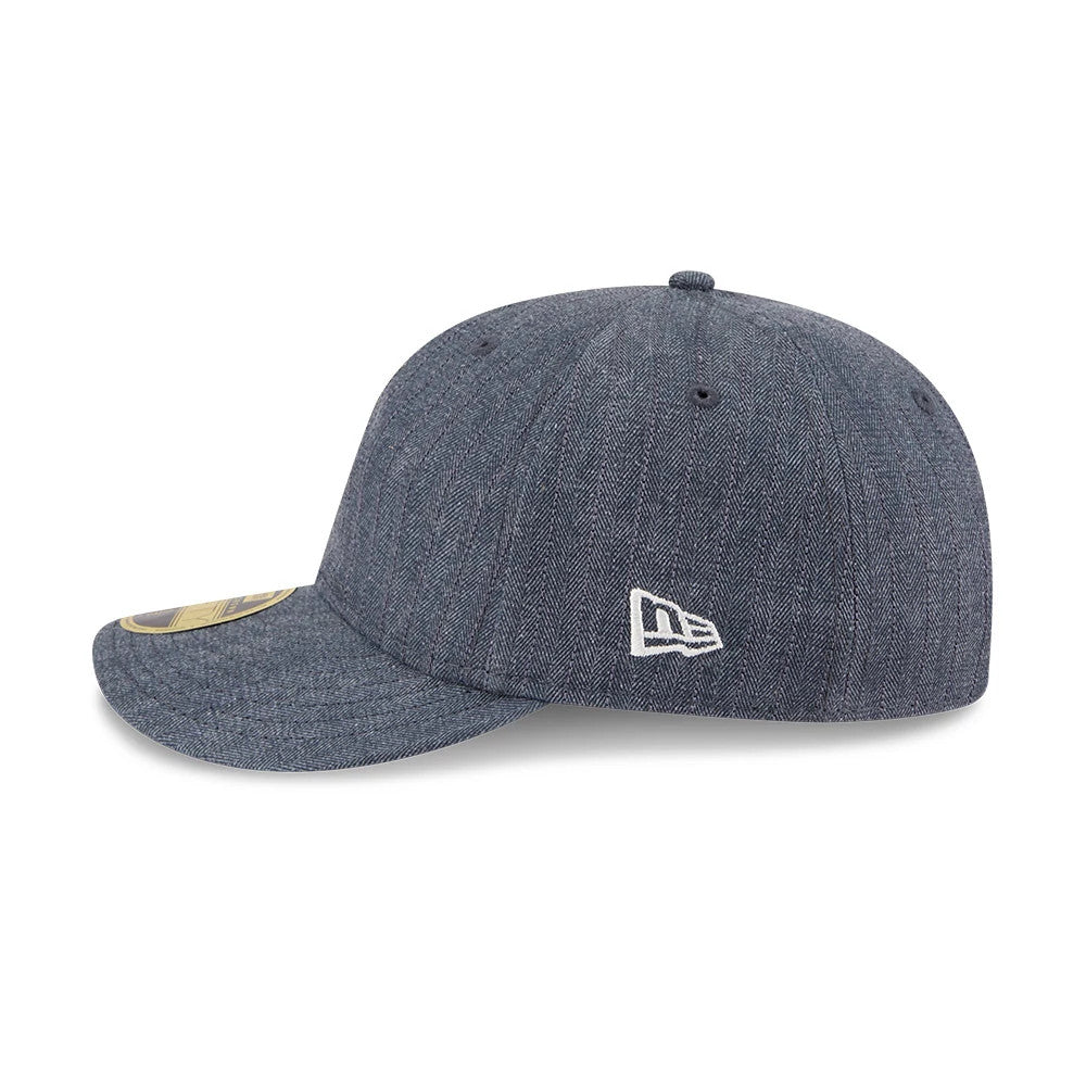 New Era Herringbone Navy Retro Crown 59FIFTY Fitted Cap, side view showing the raised white embroidered New Era flag logo on the left side, structured navy herringbone crown, and a gold 59FIFTY size sticker on the flat visor.