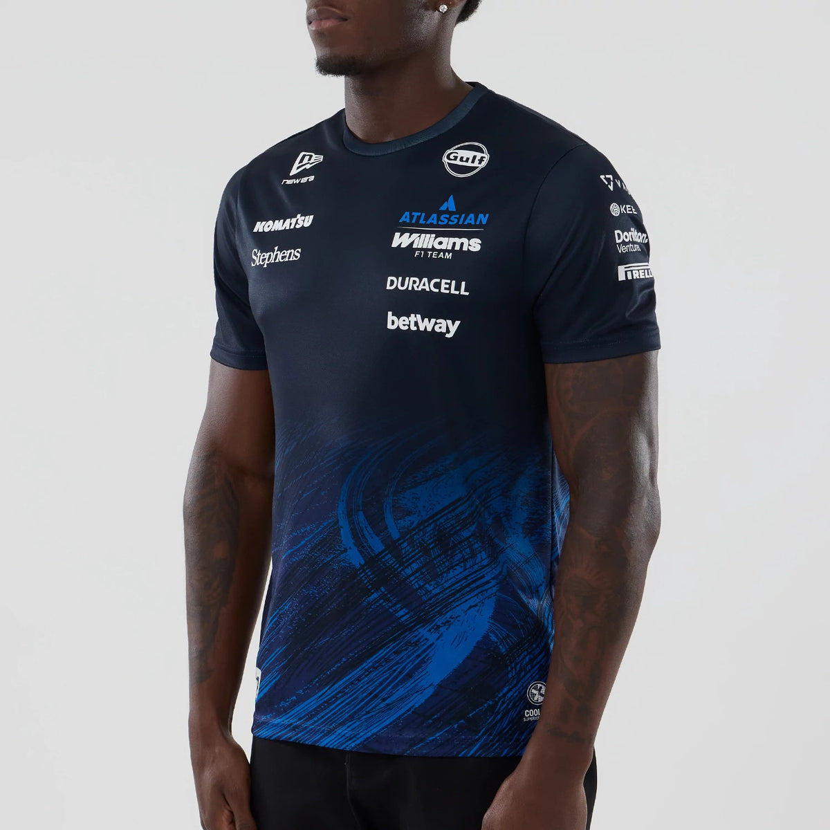 New Era Williams Alex Albon Navy Tech T-shirt, three-quarter view on a model displaying printed sponsor logos across the chest and sleeves, with dynamic blue graphic elements swirling around the lower torso.