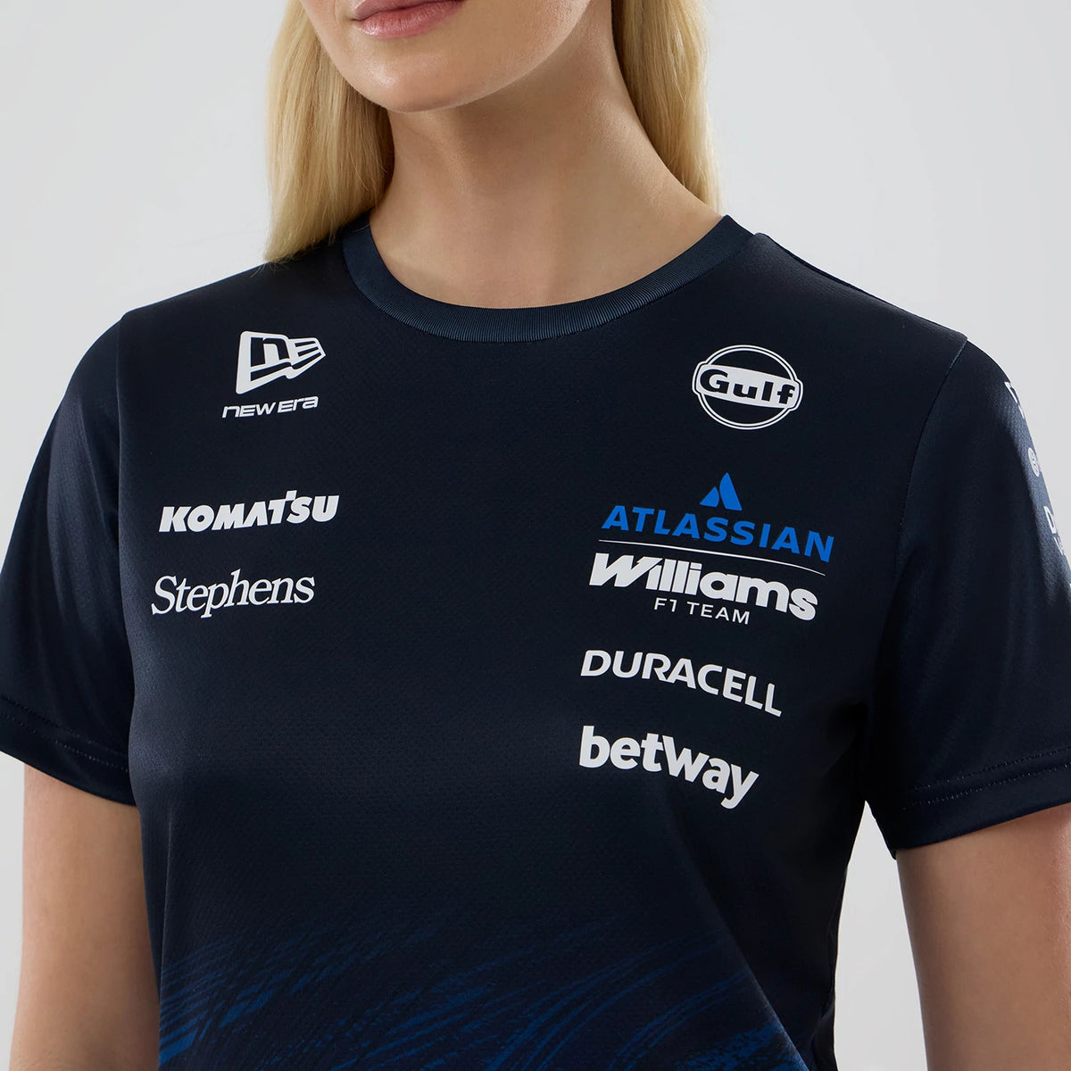 New Era Williams Womens Navy Tech T-shirt, front view on-model showcasing multiple printed sponsor logos, including New Era, Gulf and Williams F1 Team, on the upper chest of the navy blue shirt with a round neckline and short sleeves.