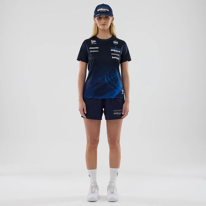 New Era Williams Womens Navy Tech T-shirt, front view on-model featuring a navy design with dynamic blue graphics on the lower half, various white sponsor logos across the chest, and a New Era logo on the sleeve; styled with matching shorts and cap.