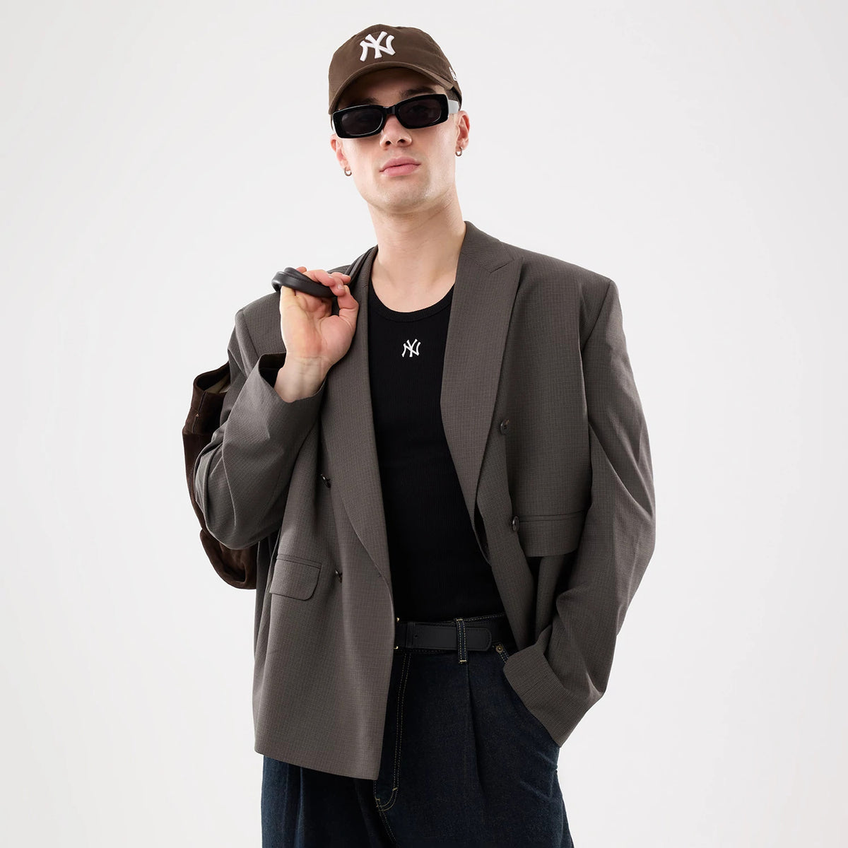 New Era New York Yankees MLB Rib Black Vest, on-model view with the vest styled under a grey blazer and paired with a black New Era cap, showcasing the white embroidered Yankees logo on the front chest.