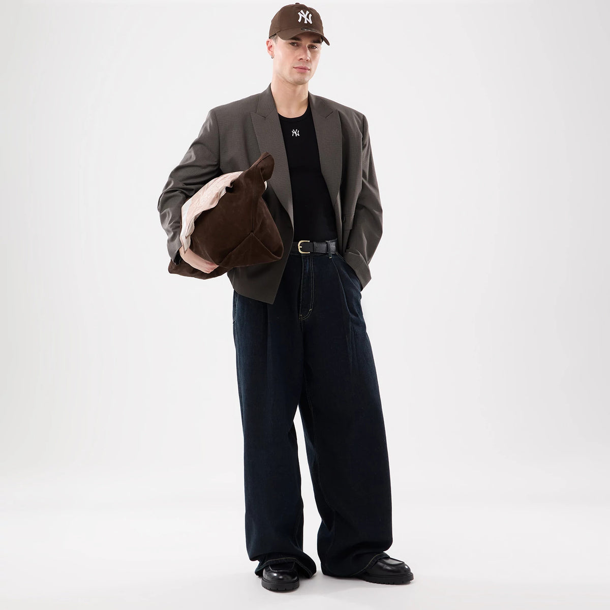 New Era New York Yankees MLB Rib Black Vest, on-model view featuring a black vest with an embroidered Yankees logo on the chest, styled under a brown blazer and paired with wide-leg denim trousers, accessorised with a brown Yankees cap.