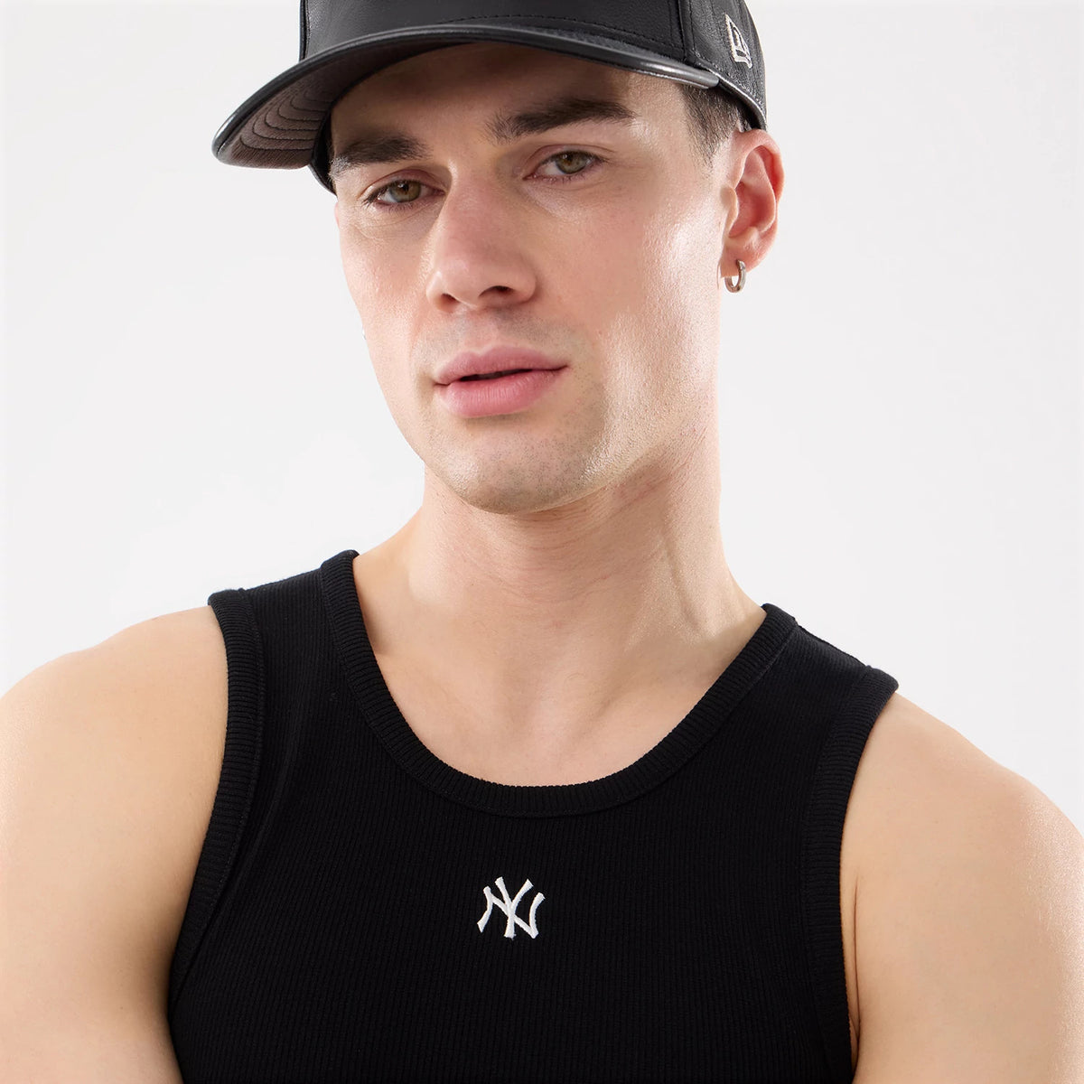 New Era New York Yankees MLB Rib Black Vest, on-model view featuring a black ribbed texture with a contrasting white embroidered NY logo on the chest, paired with a black cap showing the New Era flag logo on the left side.