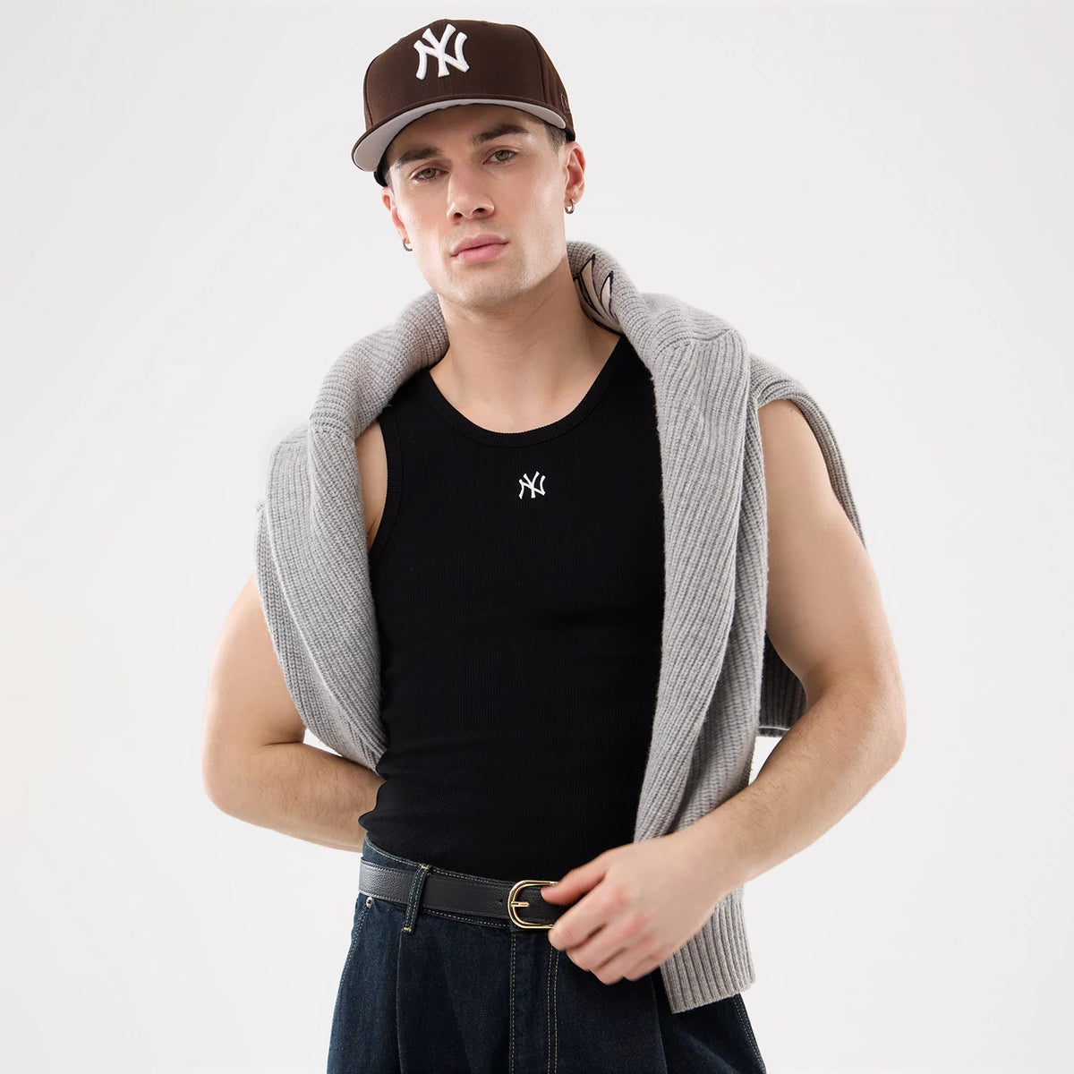 New Era New York Yankees MLB Rib Black Vest, front view on a model styled with a grey cardigan draped over the shoulders, featuring a white embroidered Yankees logo on the chest of the black vest and paired with dark jeans.