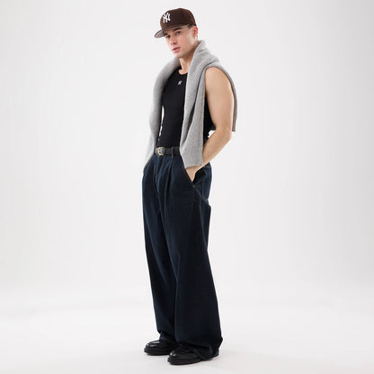 New Era New York Yankees MLB Rib Black Vest, on-model front view with the black sleeveless vest featuring a small New York Yankees logo on the chest, styled casually over a white-collared shirt and grey knitwear draped around the shoulders.