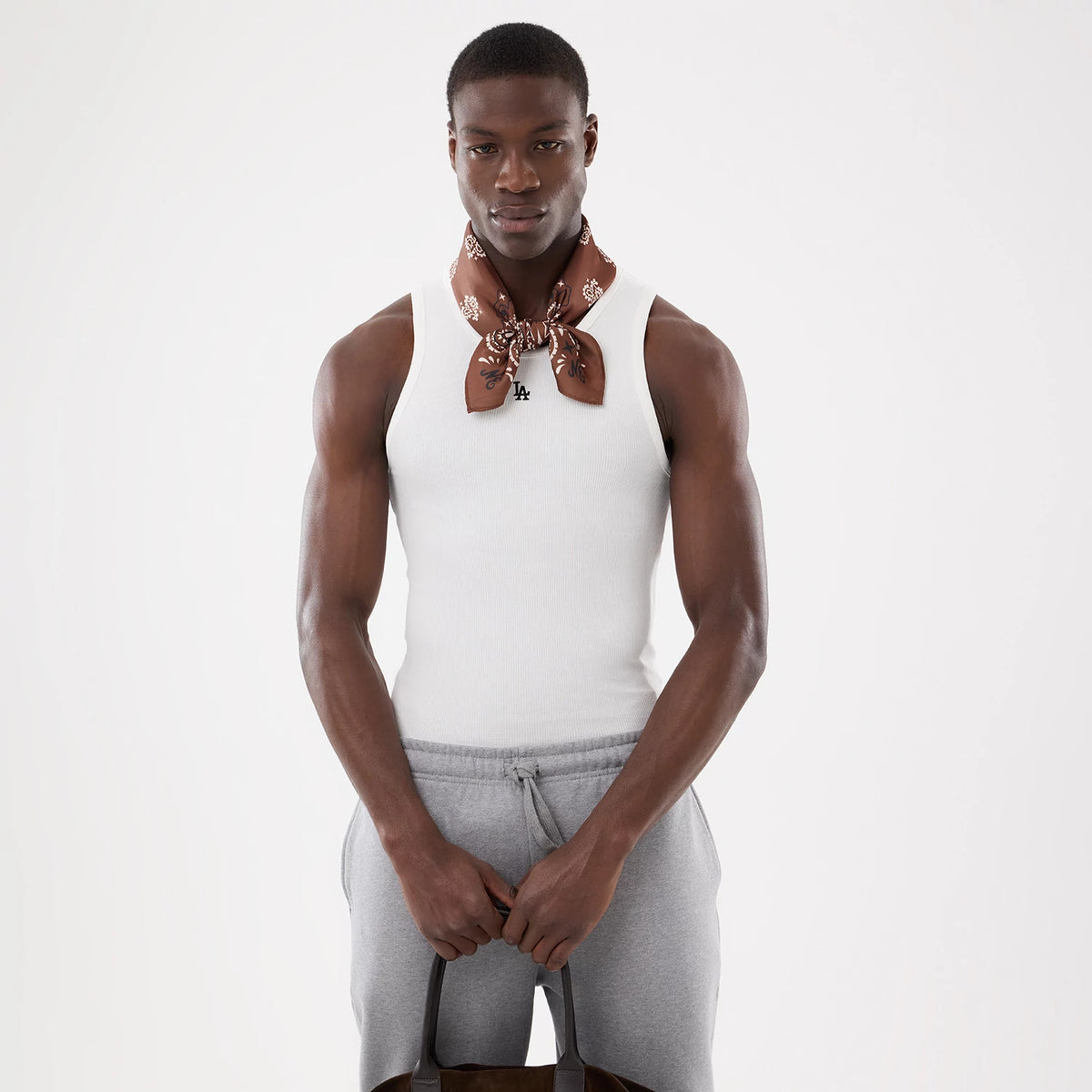 New Era LA Dodgers MLB Rib White Vest, front view on a model wearing a brown patterned scarf, showing the ribbed texture and the black LA logo embroidered on the chest, paired with light grey drawstring trousers.