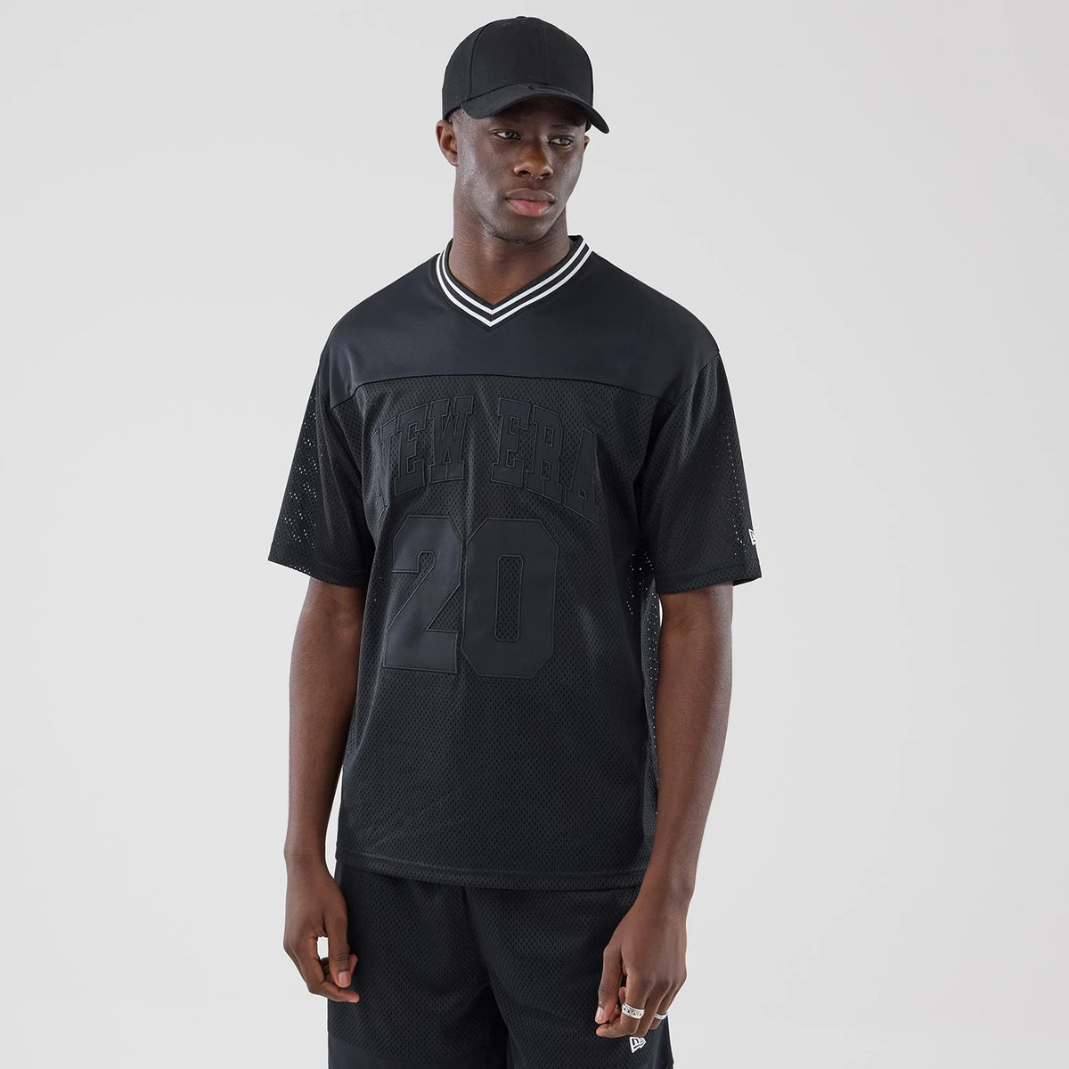 The model is wearing this New Era Mesh Oversized T-Shirt in black. 1