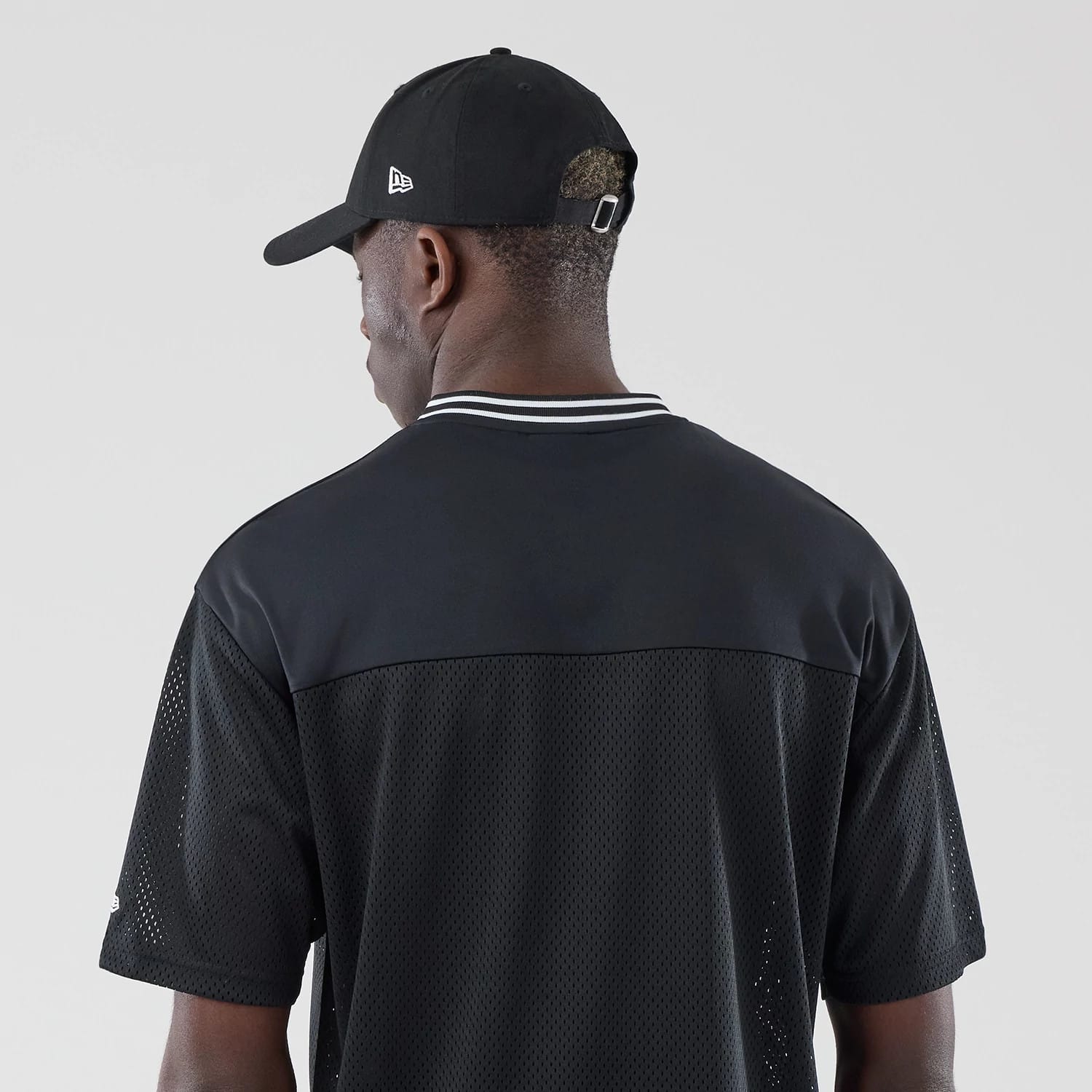 The model is wearing this New Era Mesh Oversized T-Shirt in black. 7