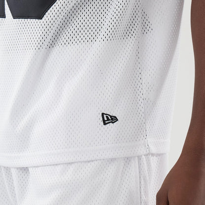 New Era Mesh White Oversized T-Shirt, side view highlighting the mesh fabric with a texture, a small black embroidered New Era logo near the hem, and the relaxed silhouette ending over matching white shorts.