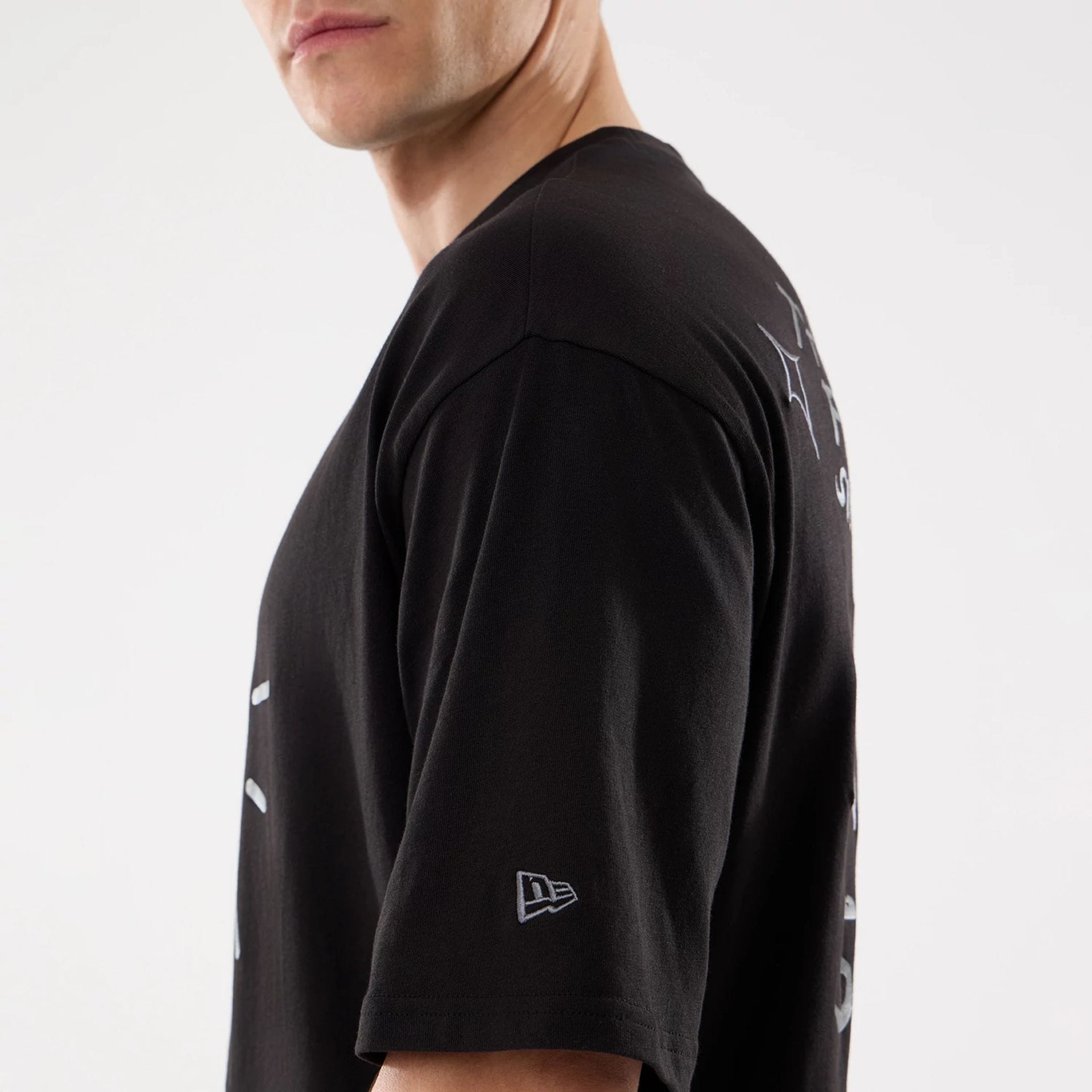 The model is wearing this New Era 59FIFTY Day Graphic T-Shirt in black. 6