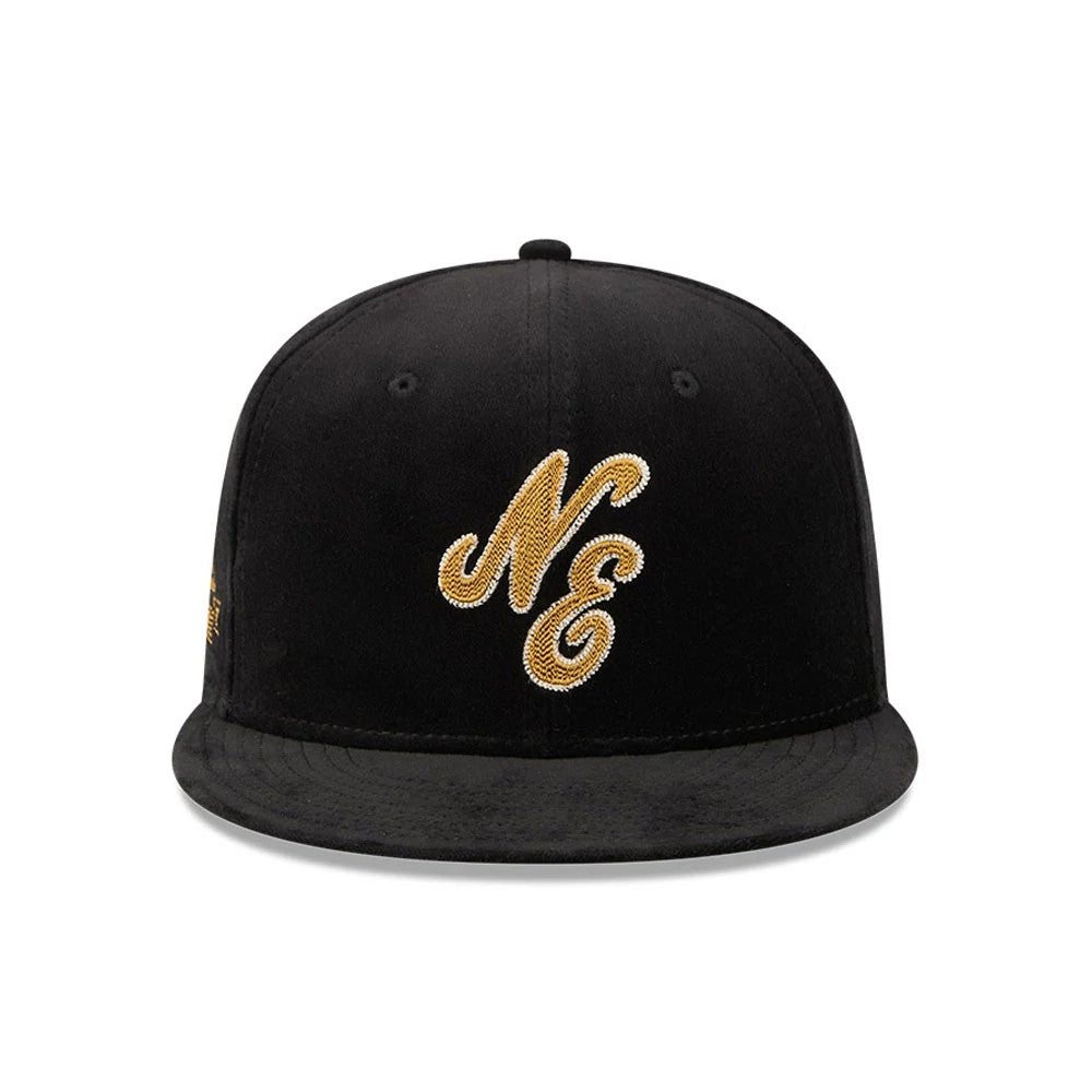New Era 59FIFTY Day Sidepatch Black 59FIFTY Fitted Cap, front view showing a gold NE logo in raised embroidery on the structured black crown, with a flat black visor and black top button.