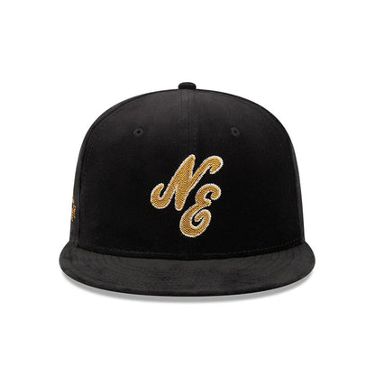 New Era 59FIFTY Day Sidepatch Black 59FIFTY Fitted Cap, front view showing a gold NE logo in raised embroidery on the structured black crown, with a flat black visor and black top button.
