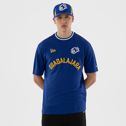 New Era Charros De Jalisco LMB Blue Oversized T-Shirt, front view on a model wearing a matching New Era cap, showing the Guadalajara lettering in yellow across the chest, an embroidered team logo on the upper left chest.