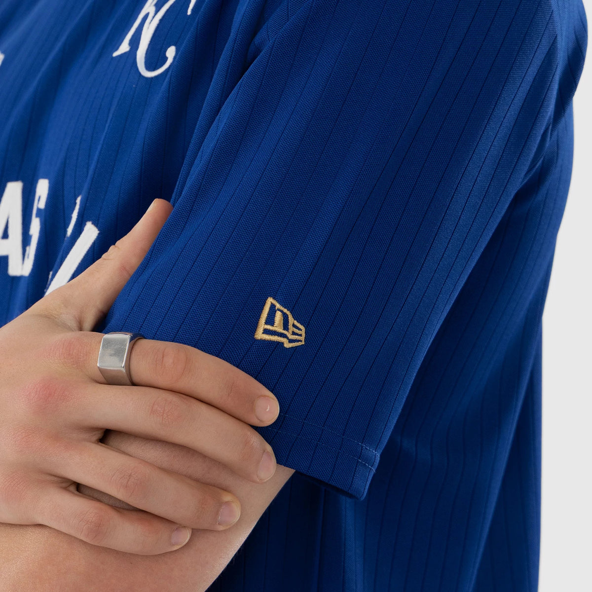 New Era Kansas City Royals MLB Blue Oversized T-Shirt, side view on a model highlighting the blue fabric with vertical stripes, a white embroidered KC on the chest, and a golden embroidered New Era logo on the sleeve.