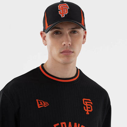New Era San Francisco Giants MLB Black Oversized T-Shirt, front view on a model also wearing a black cap with an embroidered Giants logo in high contrast orange and white, an embroidered New Era logo on the left chest, and orange accents.