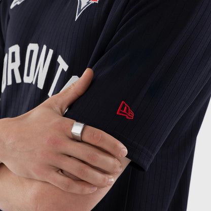 New Era Toronto Blue Jays MLB Navy Oversized T-Shirt, on-model view showing the right sleeve with a red embroidered New Era logo, navy fabric with pinstripes, and a view of white Toronto lettering across the chest.