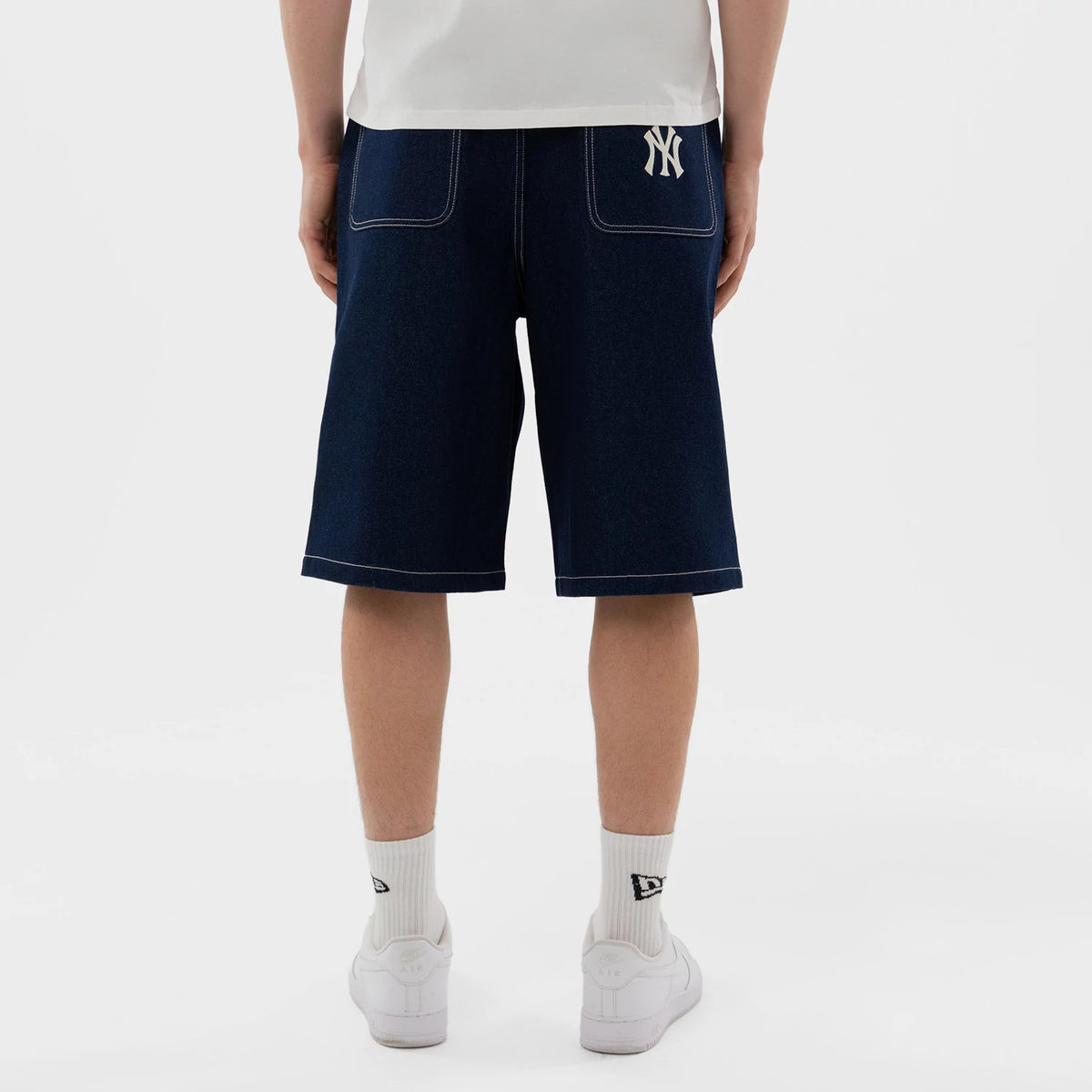 New Era New York Yankees MLB Jort Dark Blue Oversized Shorts, back view on a model showing the dark blue fabric with two large rear pockets outlined in white stitching, and a white embroidered New York Yankees logo on the right pocket.