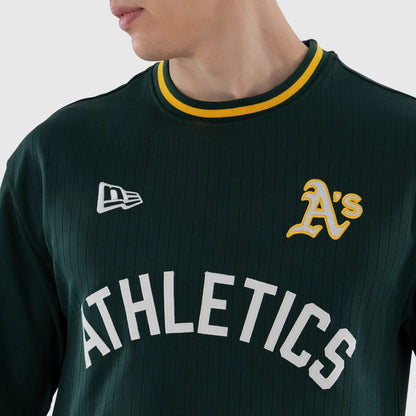 New Era Athletics MLB Dark Green Oversized T-Shirt, front view on a model showing the white embroidered New Era logo on the right chest, yellow-outlined A's emblem on the left chest, and large white Athletics lettering across the front.