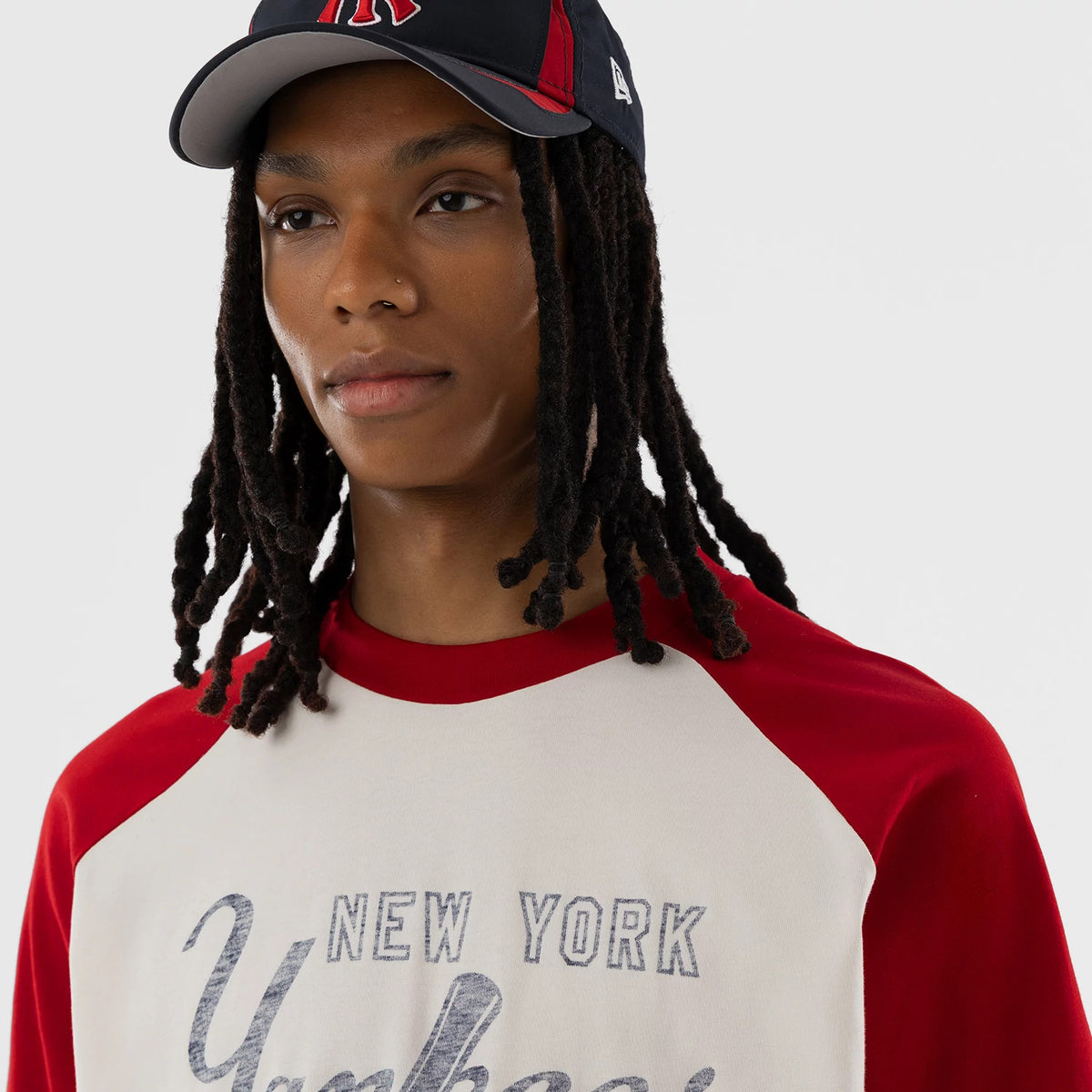 New Era New York Yankees MLB Open White Boxy T-Shirt, front view on-model showing a graphic print with faded New York Yankees text across the chest, red raglan sleeves and collar providing a contrast to the white body of the shirt.