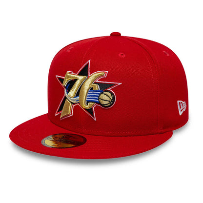 Philadelphia 76ers NBA Hardwood Classic Red New Era 59FIFTY Fitted Cap, three-quarter view showing the large gold, blue, and black embroidered 76ers logo on the front panel, complemented by a red visor and the New Era flag logo on the left side.