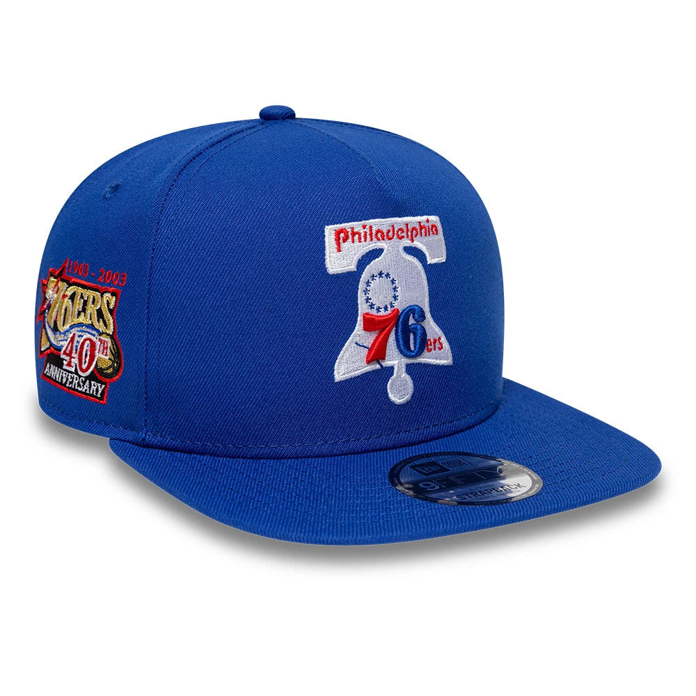 Philadelphia 76ers NBA Hardwood Classic Blue New Era 9FIFTY A-Frame Snapback Adjustable Cap, three-quarter view with a raised embroidered white bell logo and red 76ers text on the front panel, blue flat visor and a 9FIFTY size sticker.