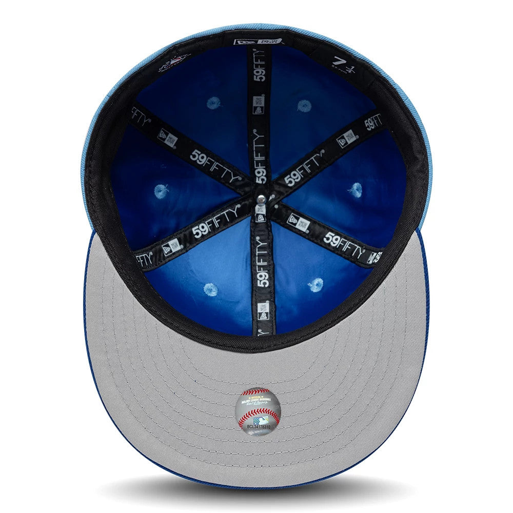 Kansas City Royals MLB Multi Logo Satin Lined Pastel Blue New Era 59FIFTY Fitted Cap, inside view showing blue satin lining, black taping with 59FIFTY logos, and a light grey undervisor with a small sticker of a baseball on the edge.
