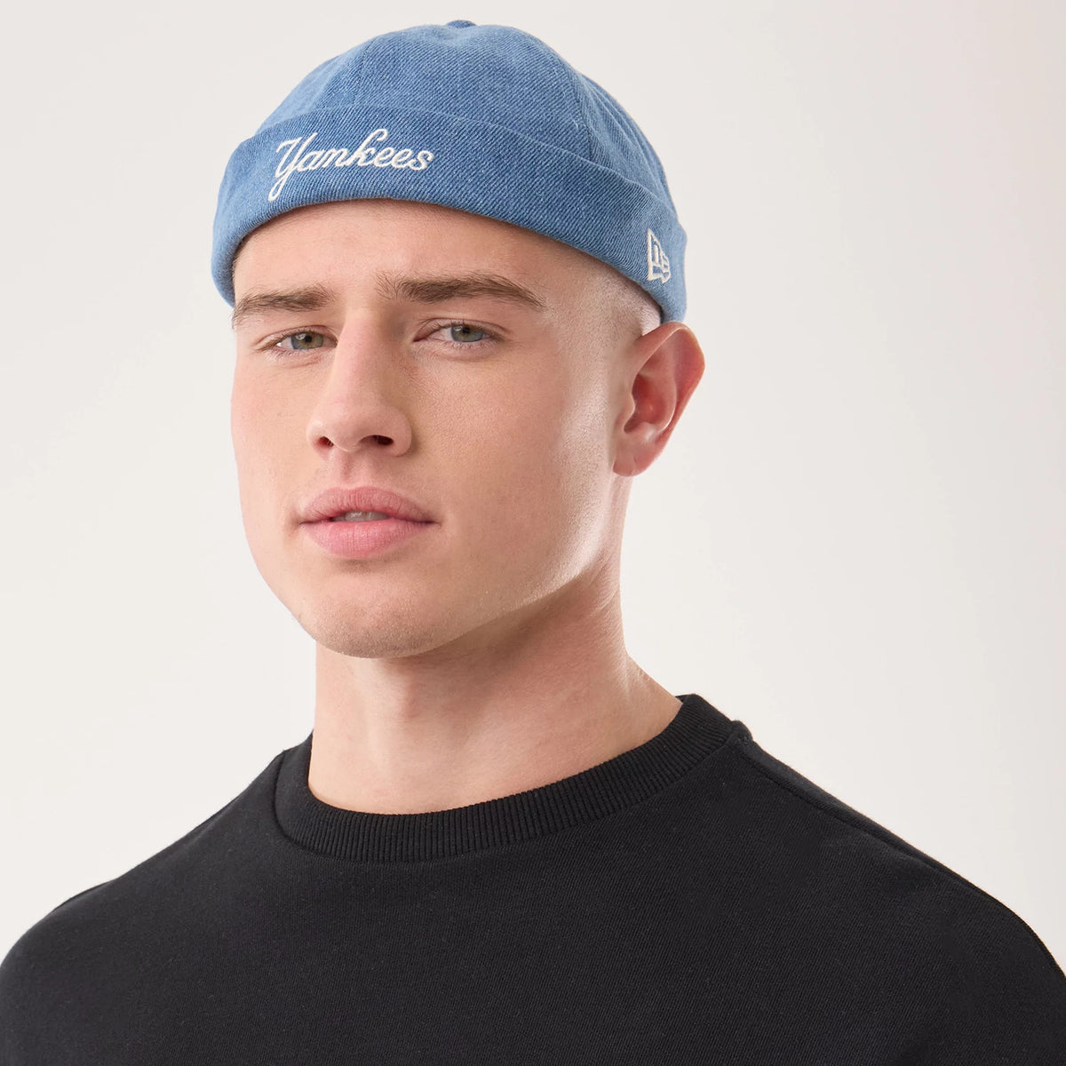 New Era New York Yankees MLB Denim Skully Pastel Blue Docker Adjustable Cap, on-model view showing the white embroidered Yankees script on the front, muted blue denim material, and the New Era flag logo embroidered on the left side.
