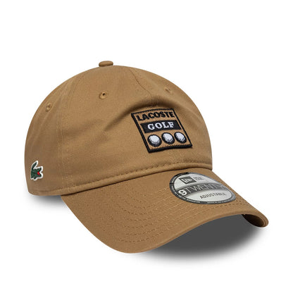 Lacoste X New Era Beige 9TWENTY Adjustable Cap, front view showing the black and white embroidered Lacoste Golf logo on the front panel, a New Era 9TWENTY size sticker on the curved visor, and the Lacoste crocodile logo on the left side.